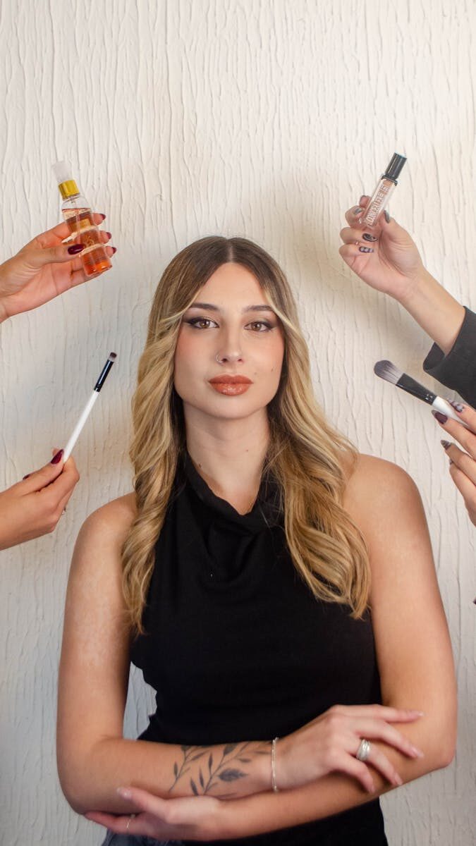 Woman posing with multiple hands holding beauty products and tools around her.